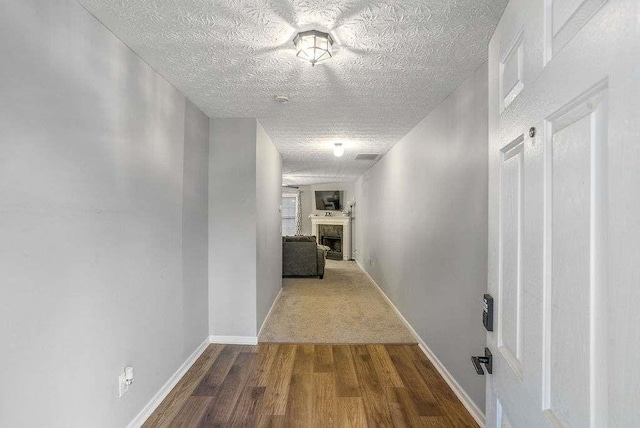 corridor with wood-type flooring and a textured ceiling