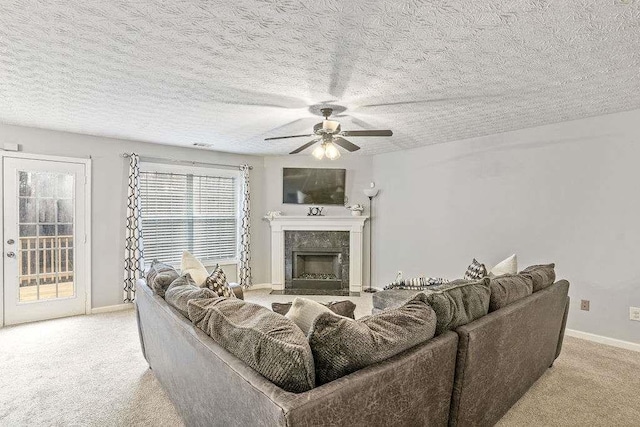 living room with a textured ceiling, a high end fireplace, light colored carpet, and ceiling fan