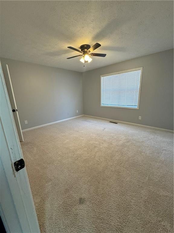 carpeted spare room with a textured ceiling and ceiling fan