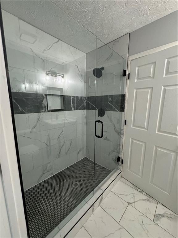 bathroom with a shower with shower door and a textured ceiling