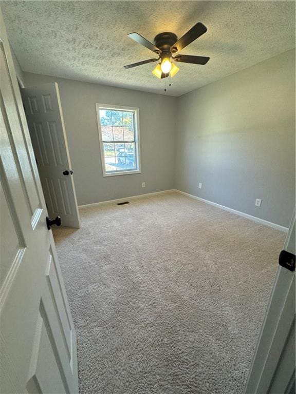 carpeted spare room with a textured ceiling and ceiling fan