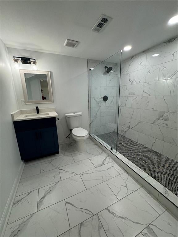 bathroom with vanity, toilet, and a tile shower