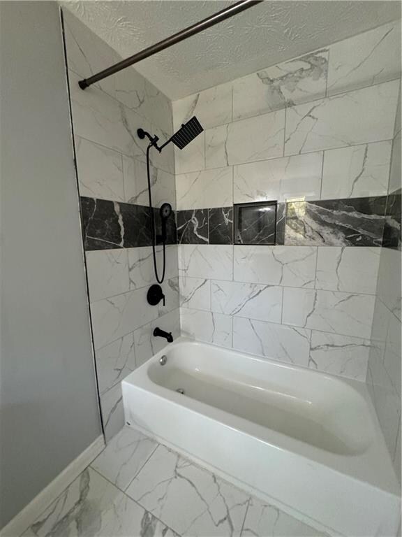 bathroom featuring tiled shower / bath and a textured ceiling