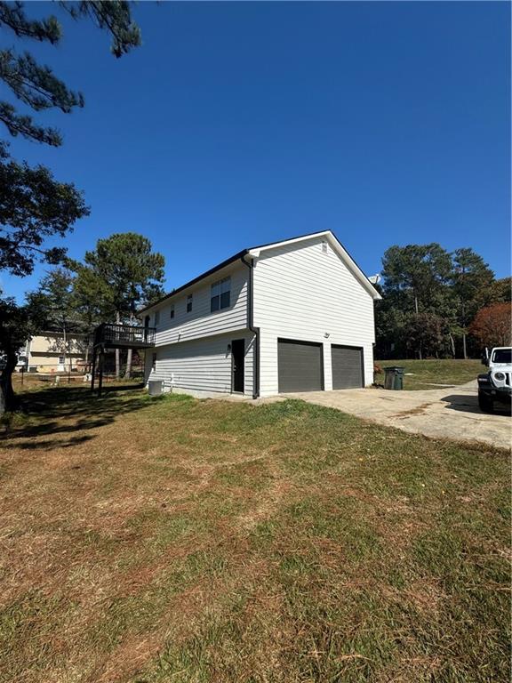 view of side of home featuring a garage, a yard, and a deck