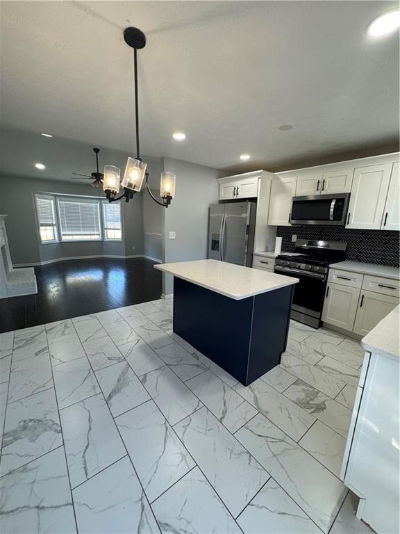 kitchen featuring a center island, white cabinets, decorative backsplash, appliances with stainless steel finishes, and decorative light fixtures