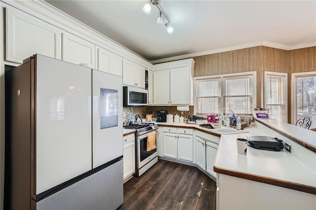 kitchen with a peninsula, a sink, freestanding refrigerator, gas stove, and crown molding