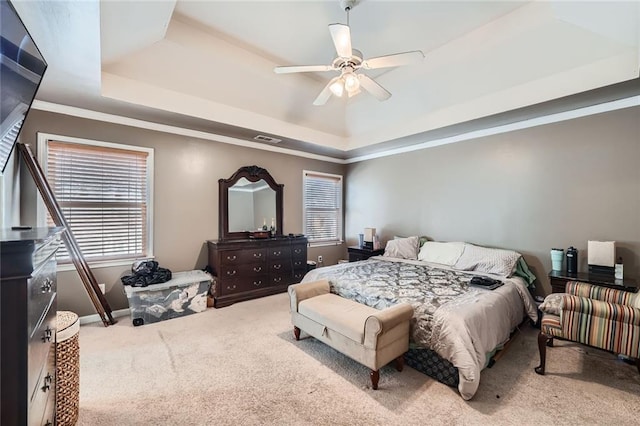 carpeted bedroom with baseboards, visible vents, a raised ceiling, and ornamental molding