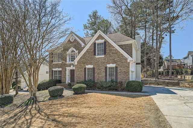 view of front facade featuring a front yard, a chimney, and brick siding