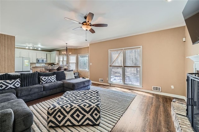 living room featuring visible vents, crown molding, baseboards, and wood finished floors