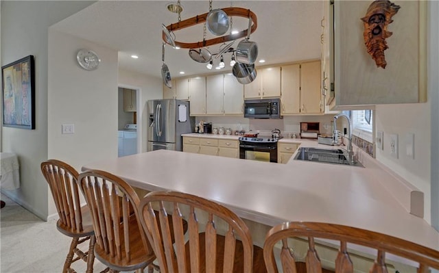 kitchen featuring black appliances, kitchen peninsula, sink, and a kitchen bar