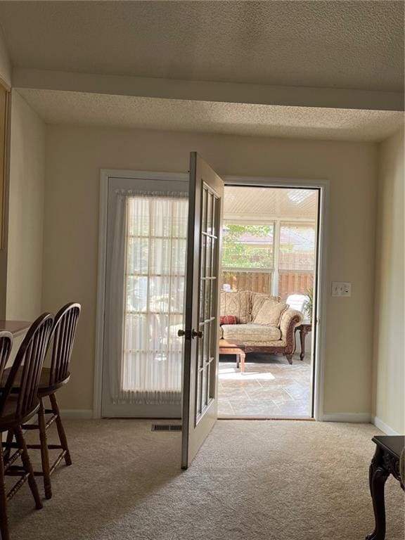entryway with a textured ceiling and light carpet