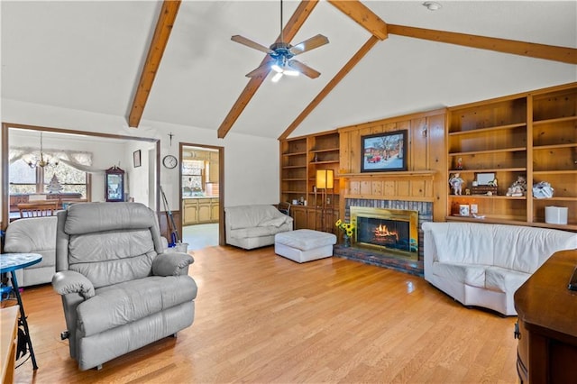 living room with beam ceiling, high vaulted ceiling, light wood-type flooring, a fireplace, and ceiling fan with notable chandelier