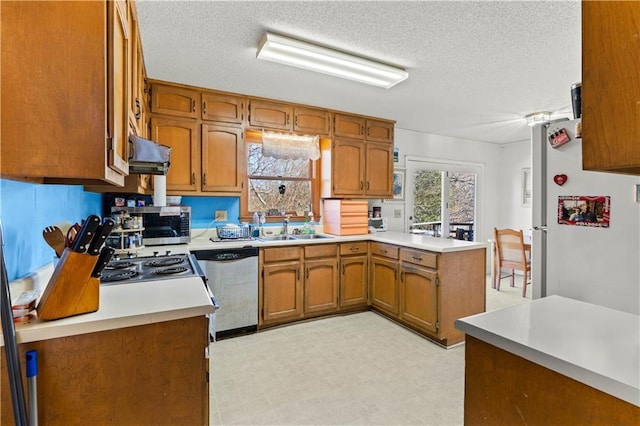 kitchen with appliances with stainless steel finishes, sink, exhaust hood, kitchen peninsula, and a textured ceiling