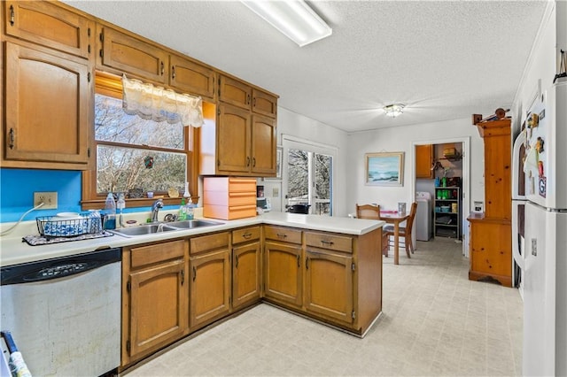 kitchen featuring washer / clothes dryer, dishwasher, sink, white fridge, and kitchen peninsula