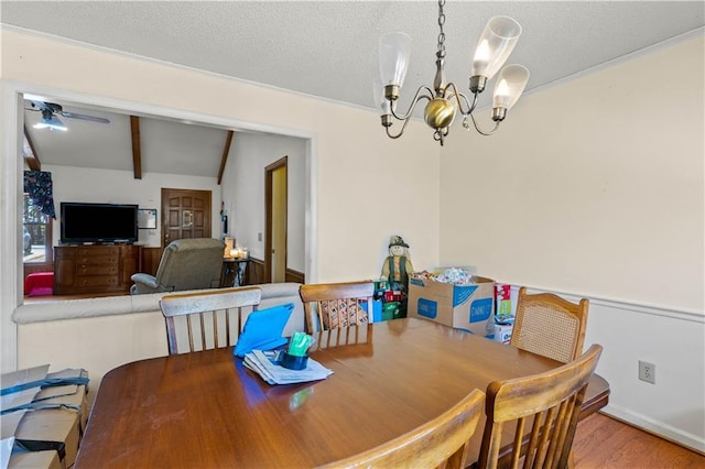 dining room with wood-type flooring, vaulted ceiling with beams, ceiling fan with notable chandelier, and a textured ceiling