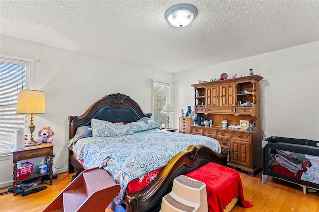 bedroom with a textured ceiling and light hardwood / wood-style floors