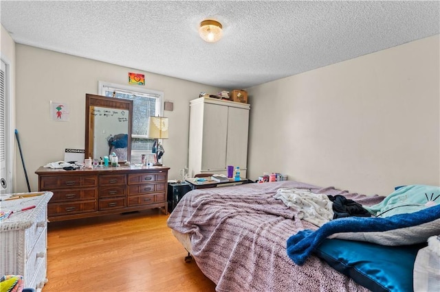 bedroom with a textured ceiling and light wood-type flooring