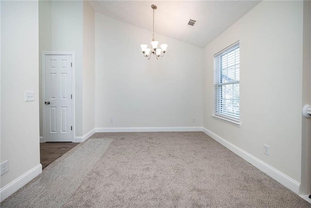 carpeted empty room featuring a chandelier and lofted ceiling