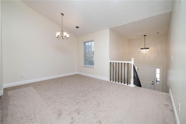 spare room with carpet flooring, a textured ceiling, vaulted ceiling, and an inviting chandelier