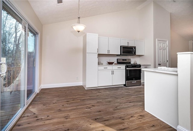 kitchen with backsplash, dark hardwood / wood-style flooring, stainless steel appliances, decorative light fixtures, and white cabinets