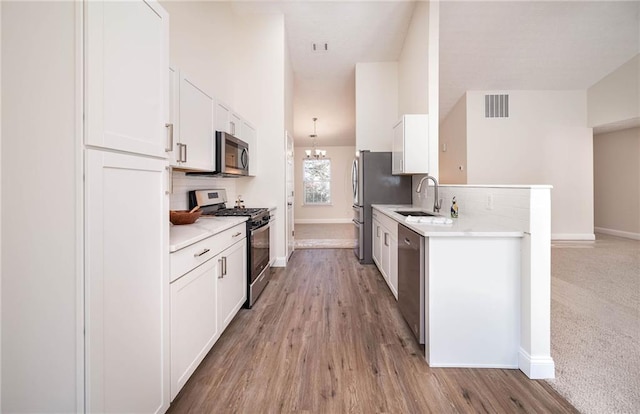 kitchen featuring white cabinetry, sink, tasteful backsplash, appliances with stainless steel finishes, and light wood-type flooring