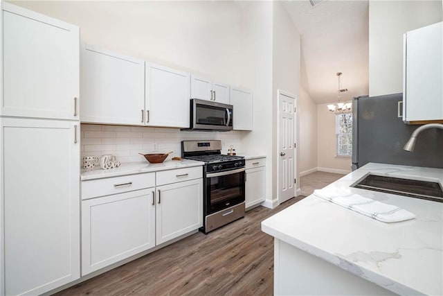 kitchen featuring sink, an inviting chandelier, high vaulted ceiling, white cabinets, and appliances with stainless steel finishes