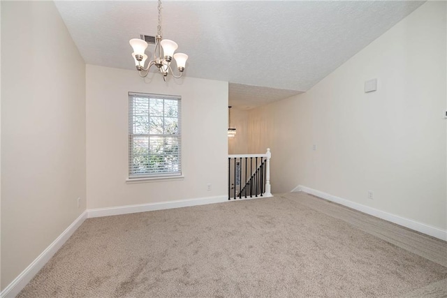 carpeted spare room featuring vaulted ceiling, a textured ceiling, and an inviting chandelier