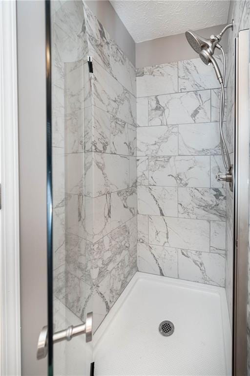 bathroom featuring a tile shower and a textured ceiling