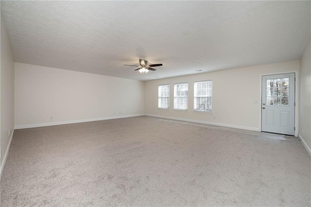 spare room featuring ceiling fan, light colored carpet, and a textured ceiling