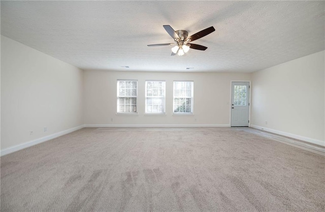 spare room with a textured ceiling, light colored carpet, and ceiling fan