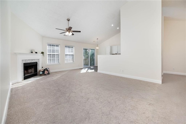 unfurnished living room featuring ceiling fan, light colored carpet, a premium fireplace, and lofted ceiling