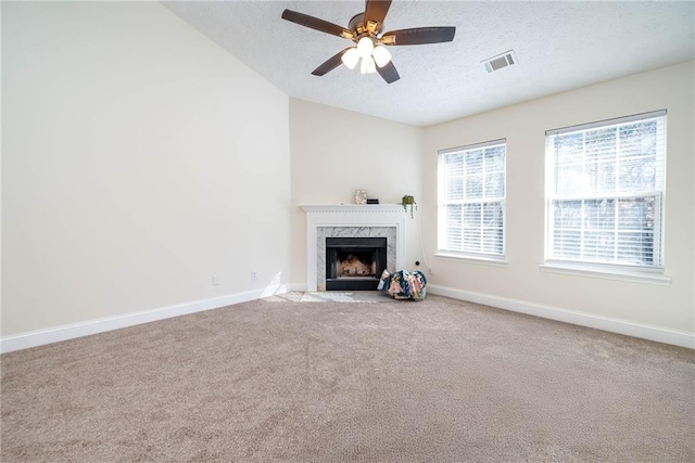 unfurnished living room with a fireplace, a textured ceiling, carpet flooring, and ceiling fan