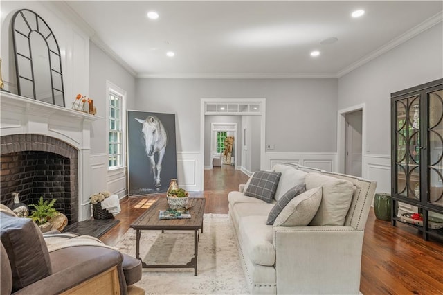 living area with a fireplace, crown molding, and wood finished floors