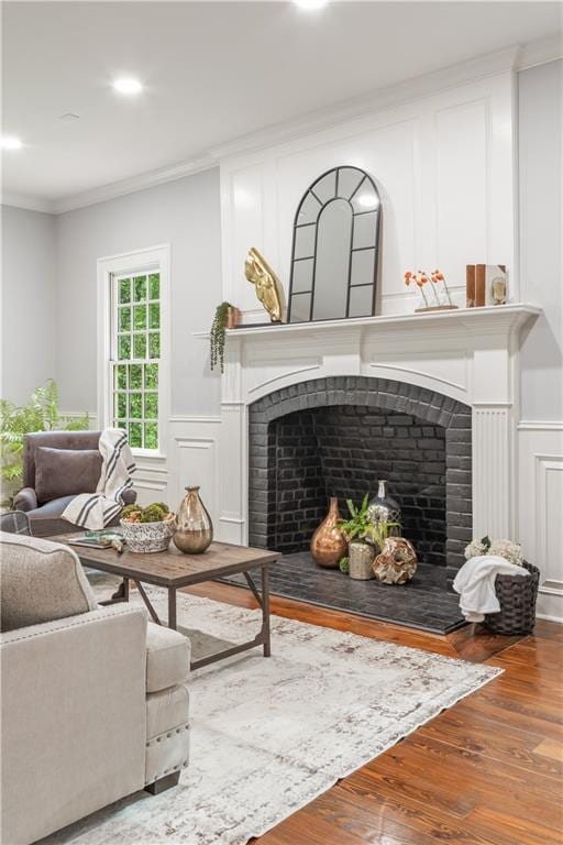 living room with hardwood / wood-style flooring, ornamental molding, and a fireplace