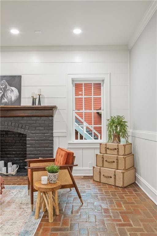 sitting room featuring brick floor, a brick fireplace, recessed lighting, and crown molding