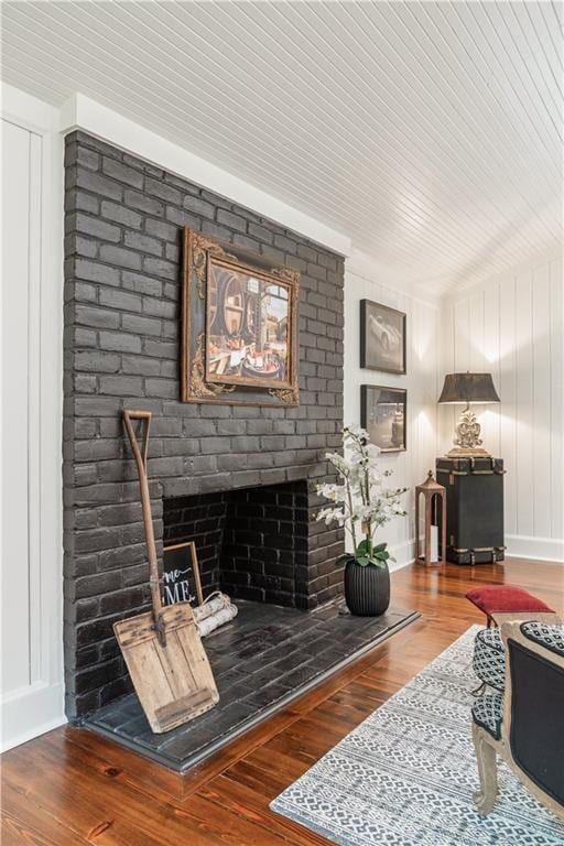 living room with a brick fireplace and wood finished floors