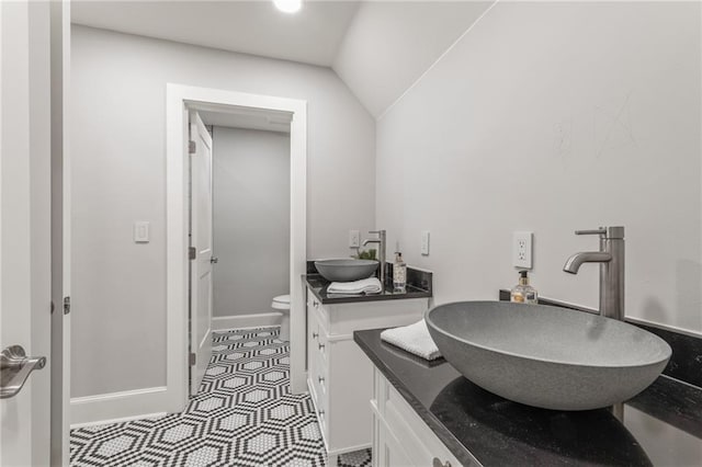 bathroom featuring toilet, vanity, lofted ceiling, and tile patterned flooring