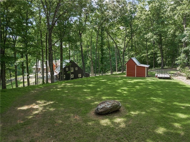 view of yard featuring a storage shed, an outdoor structure, and fence