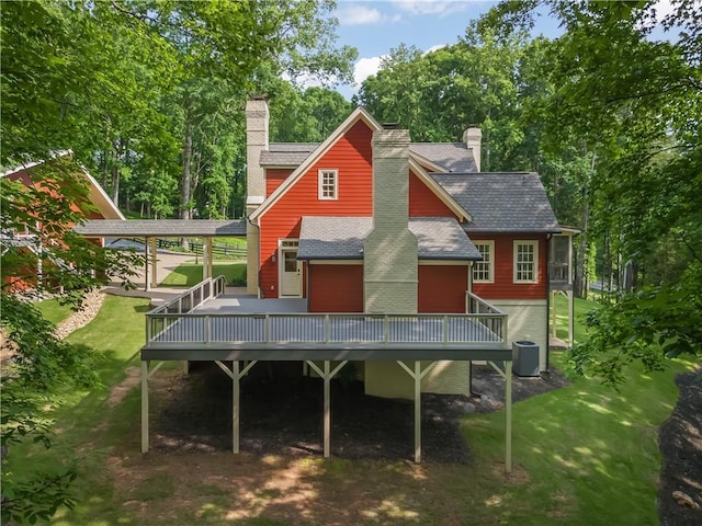 rear view of house with a deck, central air condition unit, a yard, and a chimney