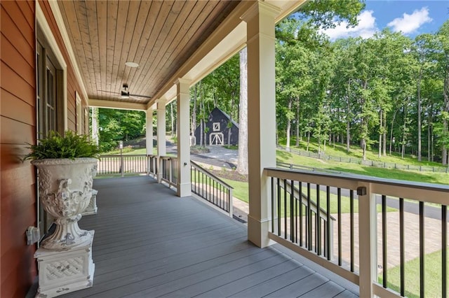 wooden terrace featuring covered porch, a lawn, and a ceiling fan