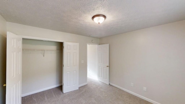 unfurnished bedroom featuring carpet floors, a closet, baseboards, and a textured ceiling