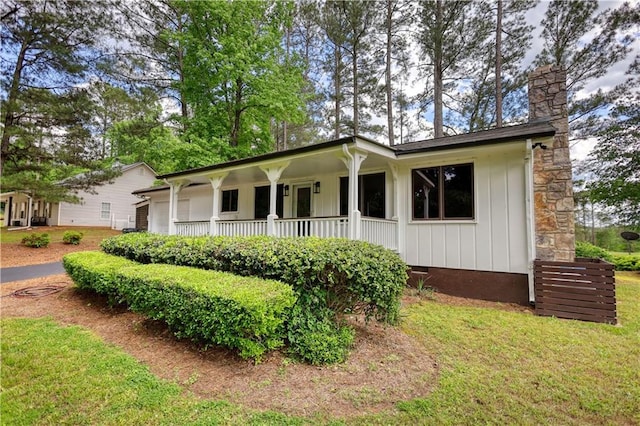 view of front of house featuring a porch, a chimney, board and batten siding, and a front lawn