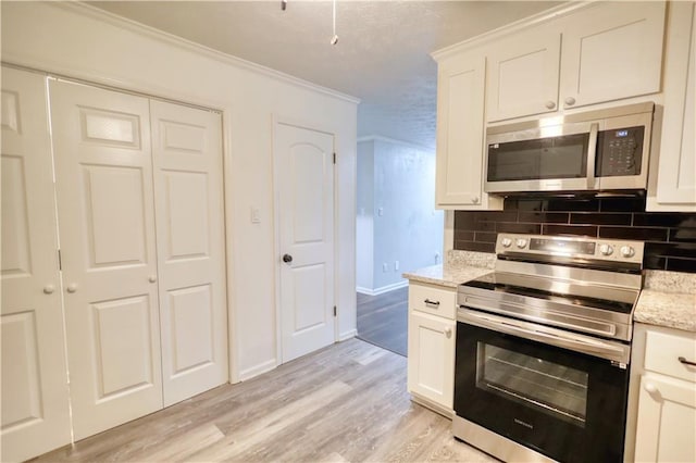 kitchen featuring stainless steel appliances, decorative backsplash, crown molding, light wood-type flooring, and light stone countertops