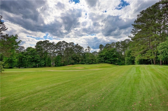 view of community with golf course view, a yard, and view of scattered trees