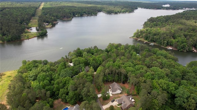 drone / aerial view of a nearby body of water and a heavily wooded area