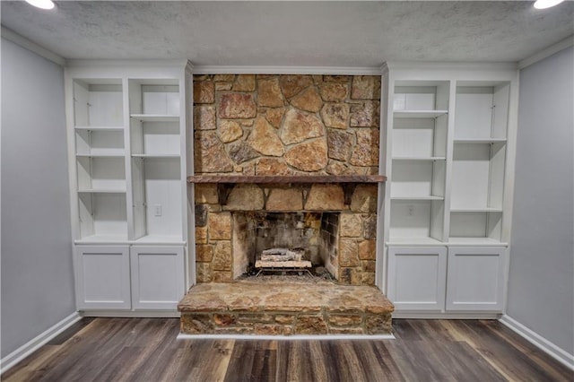 unfurnished living room featuring a textured ceiling, dark wood-type flooring, baseboards, crown molding, and a stone fireplace