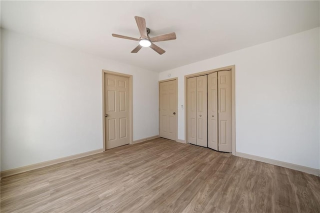 unfurnished bedroom featuring light wood-style floors, a ceiling fan, baseboards, and two closets