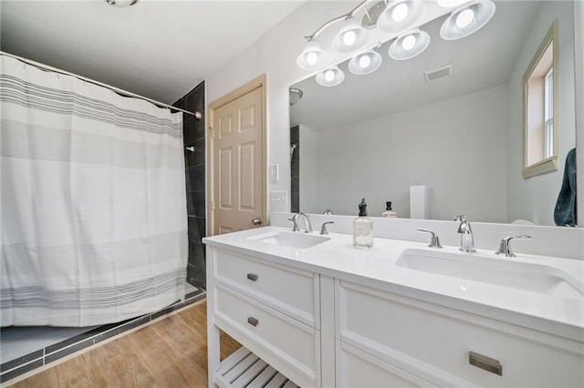 bathroom with double vanity, wood finished floors, a sink, and visible vents