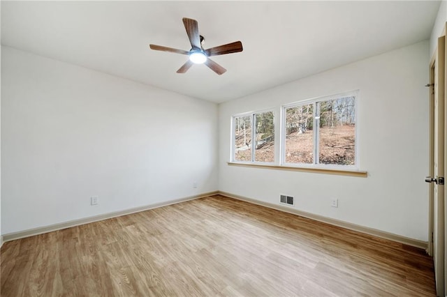 empty room with a ceiling fan, visible vents, baseboards, and wood finished floors