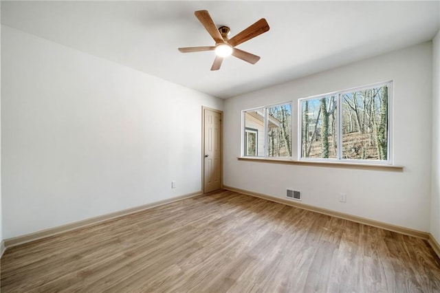 empty room featuring light wood-style flooring, visible vents, ceiling fan, and baseboards